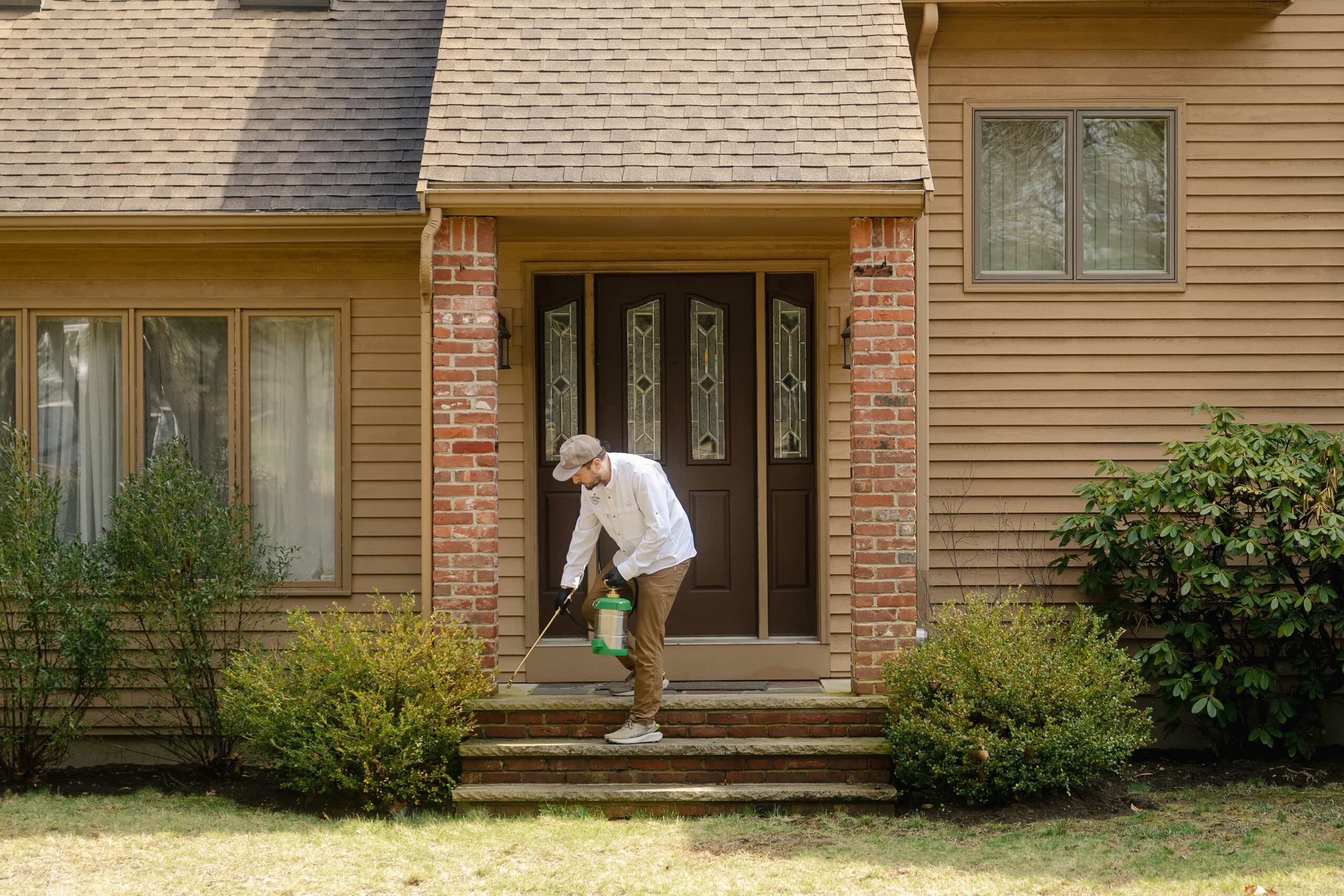 Eastern Pine Pest Control technician applying an exterior treatment to the front steps of a Massachusetts home